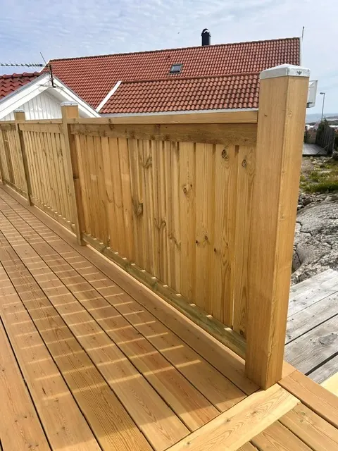 Nytt staket i stående ribbor längs ett trädäck