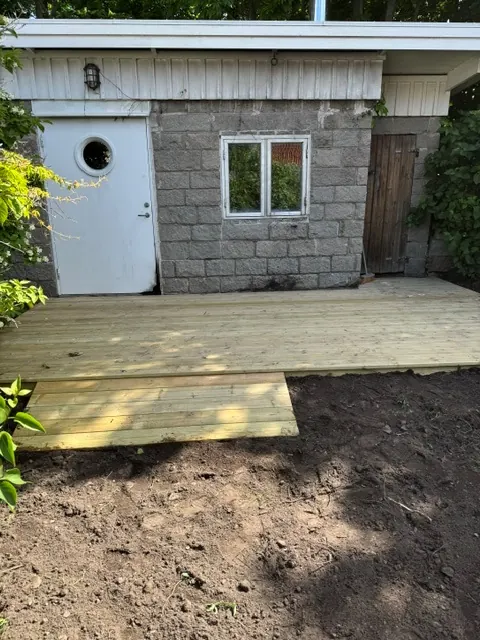 Nytt trädäck framför ett hus med stenmur