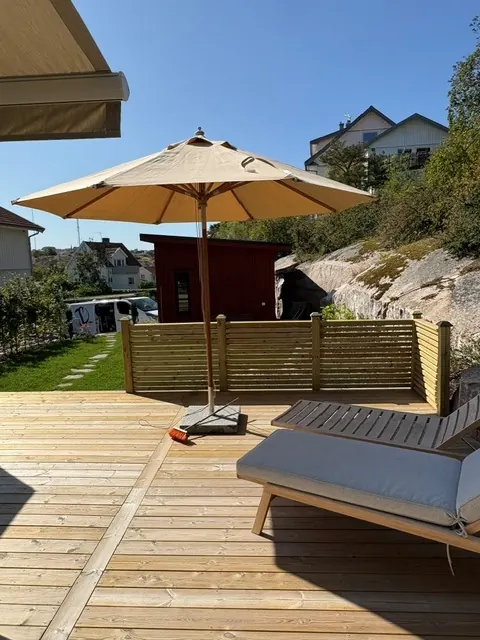 Altan med solsäng, parasoll och lågt insynsskydd i ribbor